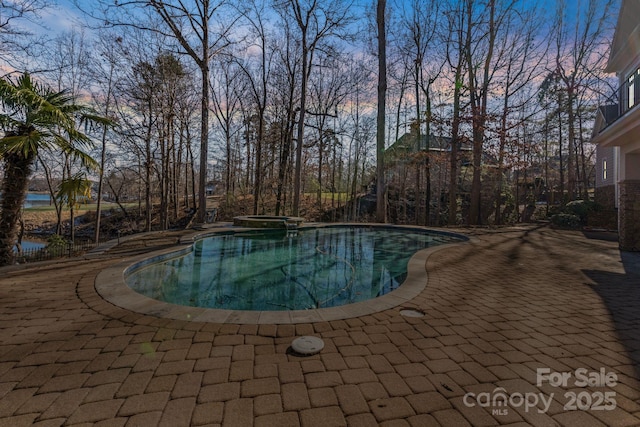 pool at dusk featuring a patio