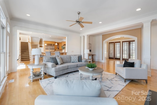 living room featuring ceiling fan, ornamental molding, light hardwood / wood-style flooring, and ornate columns