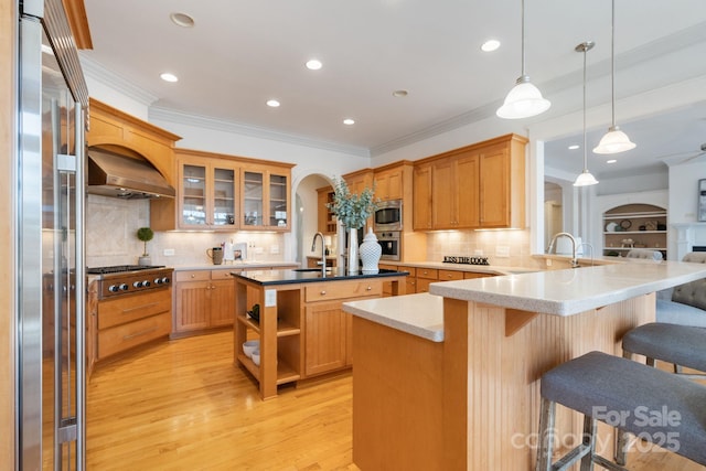 kitchen featuring sink, stainless steel appliances, a kitchen bar, decorative light fixtures, and kitchen peninsula