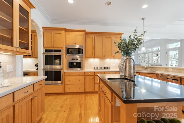 kitchen with pendant lighting, sink, stainless steel appliances, and an island with sink