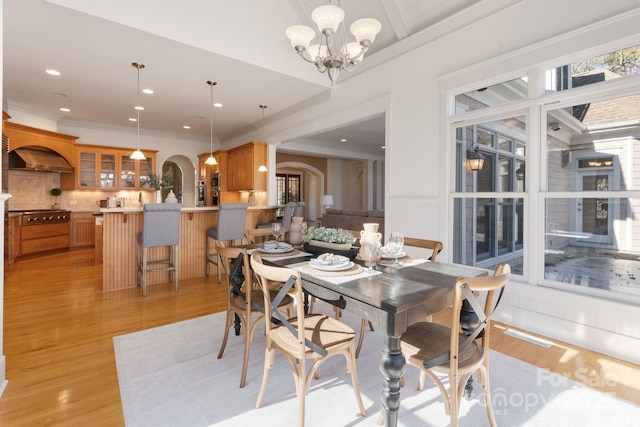 dining room with crown molding, an inviting chandelier, and light hardwood / wood-style flooring