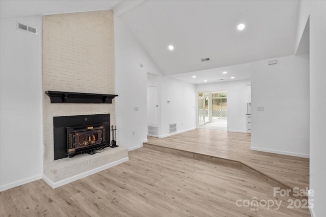 unfurnished living room with beamed ceiling, high vaulted ceiling, light wood-type flooring, and a brick fireplace