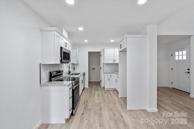 kitchen with stainless steel appliances, sink, white cabinets, and backsplash