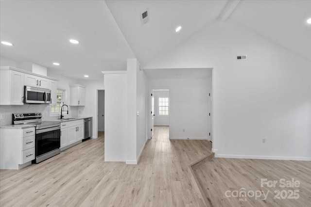 kitchen with sink, white cabinetry, stainless steel appliances, beam ceiling, and light stone countertops