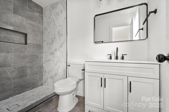 bathroom featuring tiled shower, vanity, toilet, and tile patterned flooring