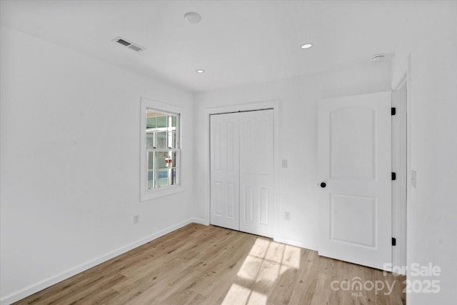 unfurnished bedroom with light wood-type flooring and a closet