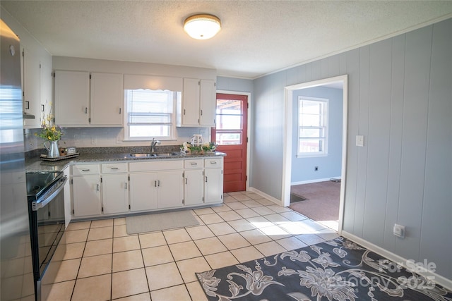 kitchen featuring sink, electric range, a textured ceiling, light tile patterned flooring, and white cabinetry