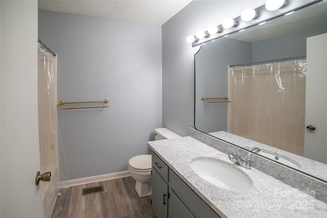 bathroom with a shower with curtain, hardwood / wood-style floors, a textured ceiling, toilet, and vanity