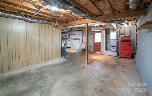 basement featuring gas water heater and wooden walls