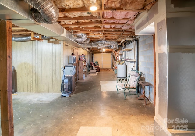 basement featuring wood walls and water heater