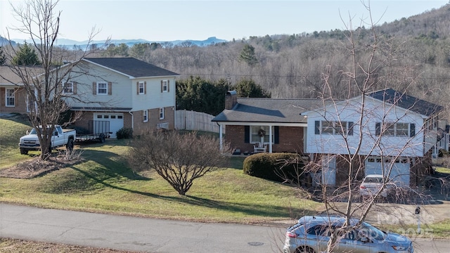 view of front facade featuring a mountain view, cooling unit, a garage, and a front yard