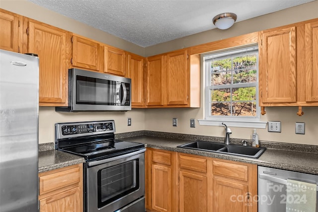 kitchen with a textured ceiling, sink, and stainless steel appliances