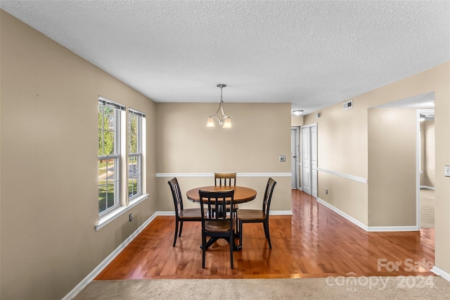 dining room with hardwood / wood-style floors, a textured ceiling, and an inviting chandelier