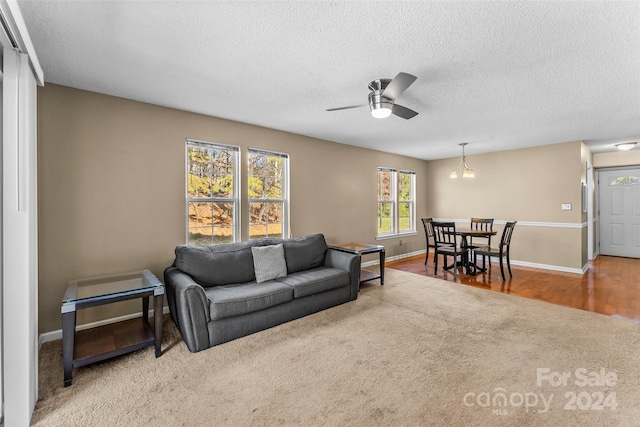 living room with hardwood / wood-style floors, ceiling fan with notable chandelier, and a textured ceiling