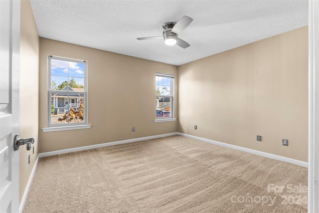 spare room featuring carpet flooring, plenty of natural light, ceiling fan, and a textured ceiling