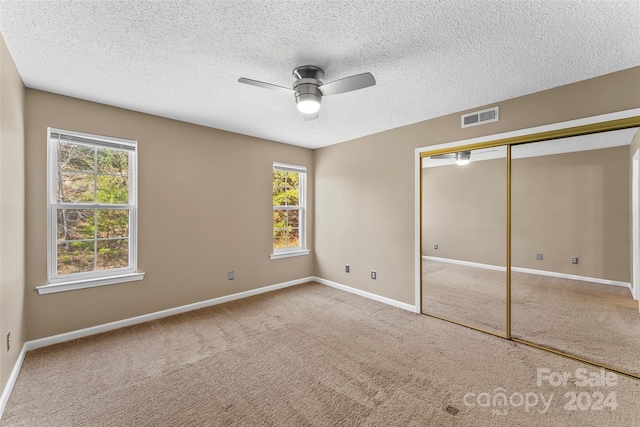 unfurnished bedroom with multiple windows, ceiling fan, a closet, and carpet floors