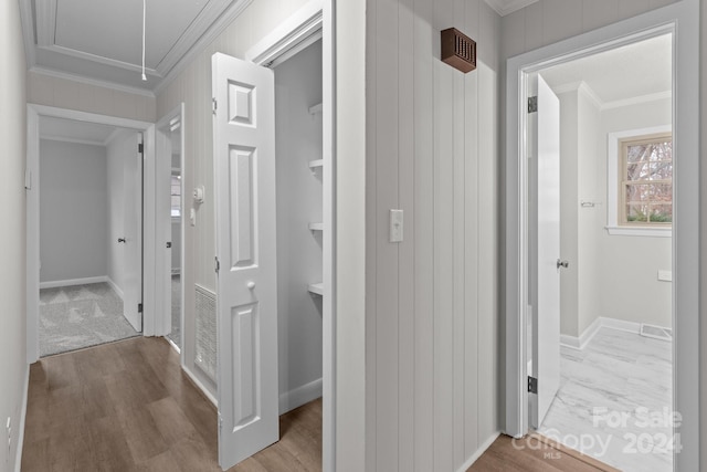 hallway featuring ornamental molding, wooden walls, and light hardwood / wood-style flooring