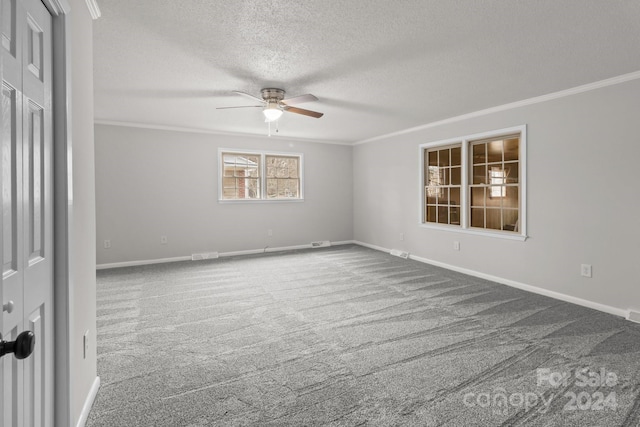 carpeted empty room featuring ceiling fan, a textured ceiling, and ornamental molding