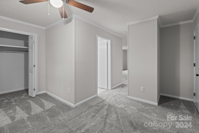 unfurnished bedroom featuring carpet, ceiling fan, crown molding, and a textured ceiling