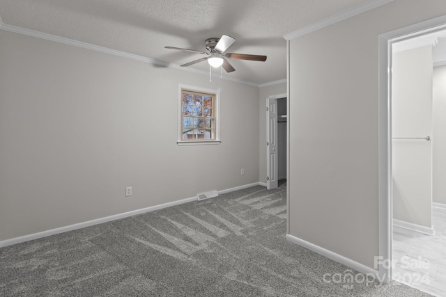 unfurnished bedroom featuring dark colored carpet, ceiling fan, crown molding, and a textured ceiling