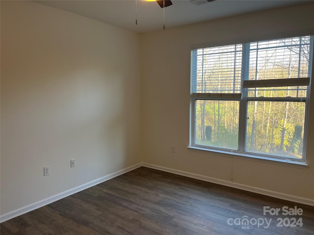 spare room featuring dark hardwood / wood-style floors, ceiling fan, and a healthy amount of sunlight