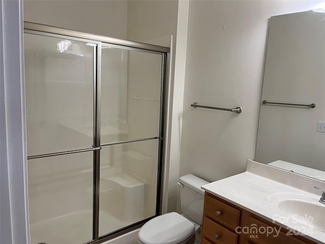 bathroom featuring vanity, an enclosed shower, and toilet