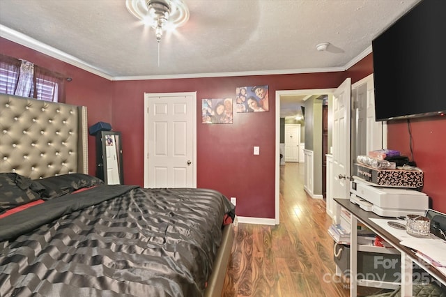 bedroom with hardwood / wood-style floors, ornamental molding, and a textured ceiling