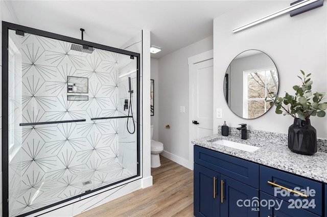 bathroom featuring toilet, vanity, an enclosed shower, and hardwood / wood-style flooring