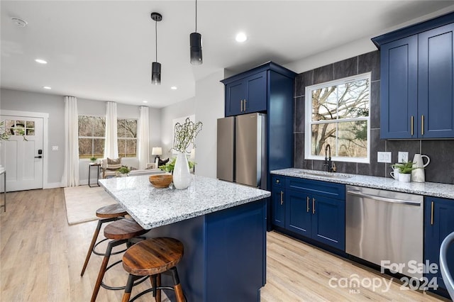 kitchen with appliances with stainless steel finishes, a center island, blue cabinets, and sink