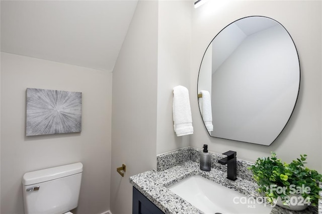 bathroom with vanity, toilet, and lofted ceiling