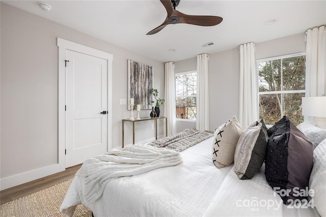 bedroom with hardwood / wood-style flooring, ceiling fan, and multiple windows