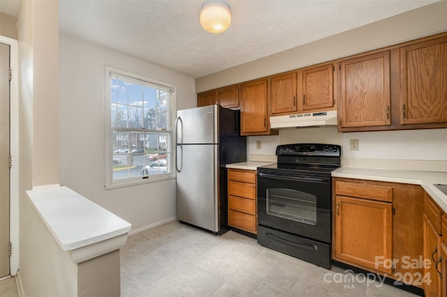 kitchen with black range with electric stovetop, stainless steel fridge, and a textured ceiling