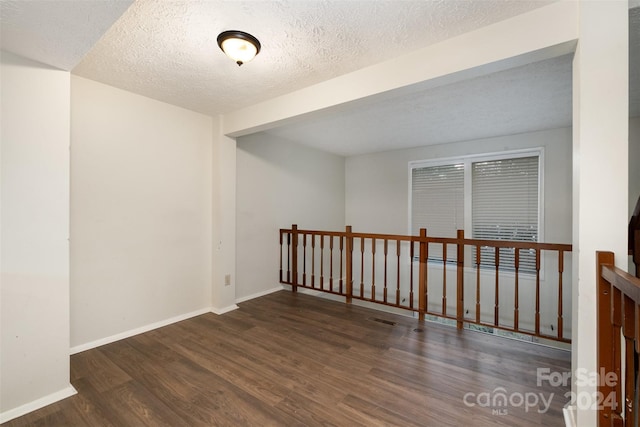 spare room featuring dark wood-type flooring and a textured ceiling