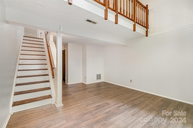 basement featuring wood-type flooring and a textured ceiling