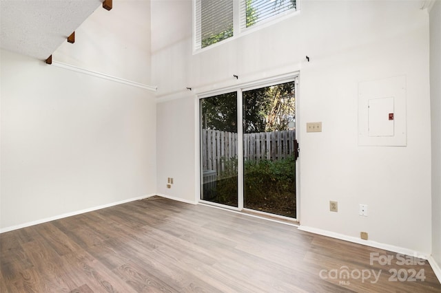 empty room featuring hardwood / wood-style floors, a high ceiling, and electric panel