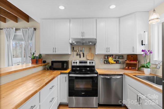 kitchen with butcher block countertops, white cabinetry, hanging light fixtures, and appliances with stainless steel finishes