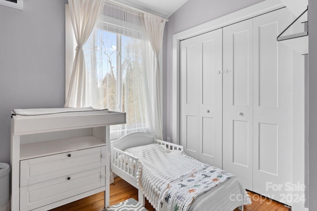 bedroom with hardwood / wood-style floors, lofted ceiling, and a closet