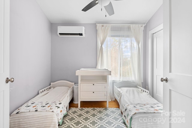 bedroom with a wall mounted AC, ceiling fan, and hardwood / wood-style flooring