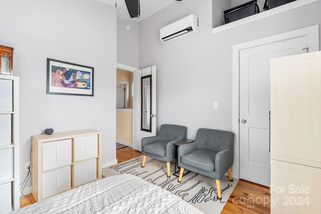 sitting room featuring wood-type flooring, a towering ceiling, a wall mounted AC, and ceiling fan