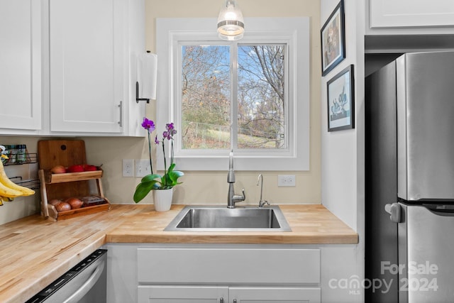 kitchen with white cabinets, wood counters, sink, and stainless steel appliances