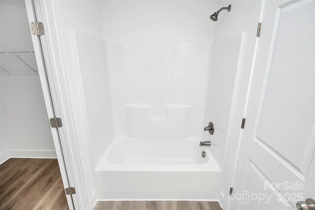 bathroom with hardwood / wood-style floors and washtub / shower combination