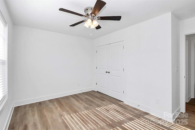 unfurnished bedroom featuring ceiling fan, wood-type flooring, and a closet