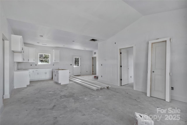 kitchen with a kitchen island, visible vents, white cabinets, vaulted ceiling, and open floor plan