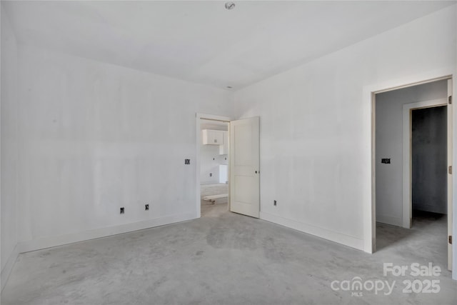 unfurnished bedroom featuring concrete flooring and baseboards