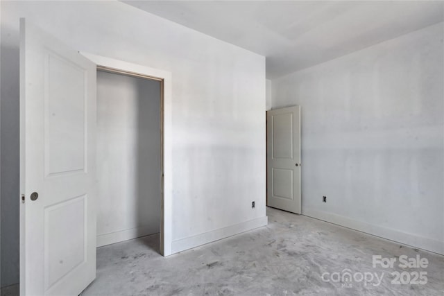 unfurnished bedroom with unfinished concrete flooring and baseboards