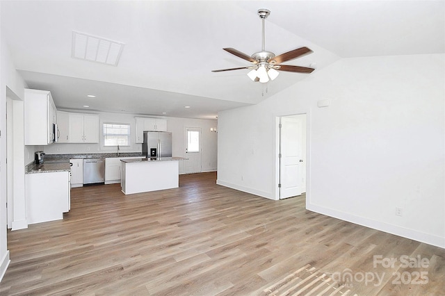 interior space with visible vents, baseboards, vaulted ceiling, a ceiling fan, and light wood-type flooring