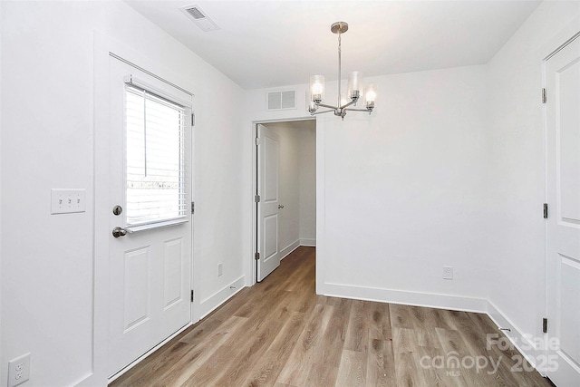 unfurnished dining area featuring a chandelier, light wood-type flooring, visible vents, and baseboards