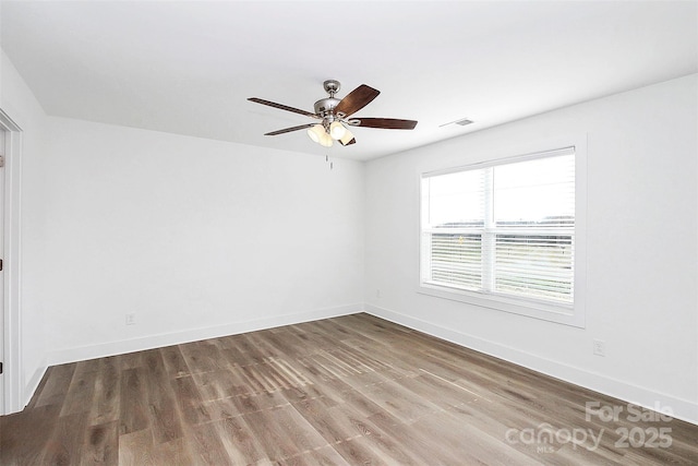 empty room with a ceiling fan, visible vents, baseboards, and wood finished floors