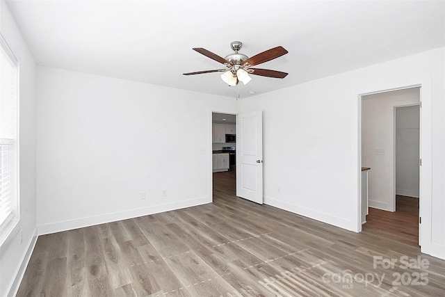 empty room featuring a ceiling fan, baseboards, and wood finished floors