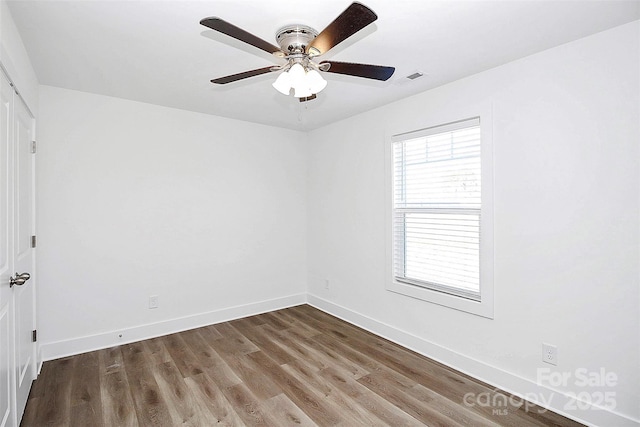 unfurnished room featuring dark wood-style floors, a ceiling fan, visible vents, and baseboards